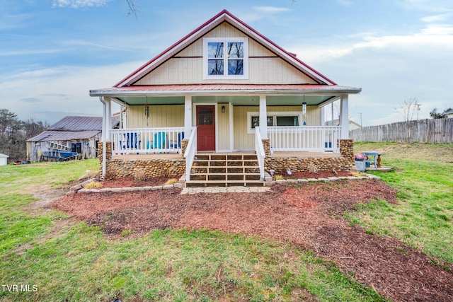 view of front of home with metal roof, a porch, a front yard, and fence