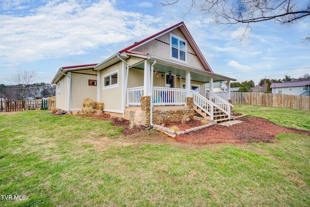 view of front of house featuring covered porch, fence, and a front lawn