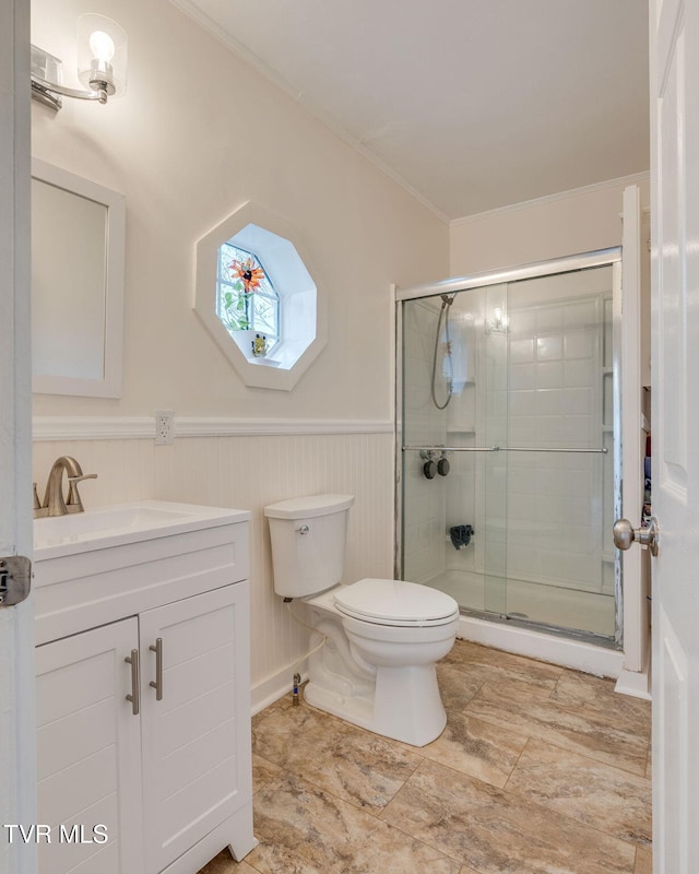 bathroom with toilet, ornamental molding, wainscoting, a shower stall, and vanity