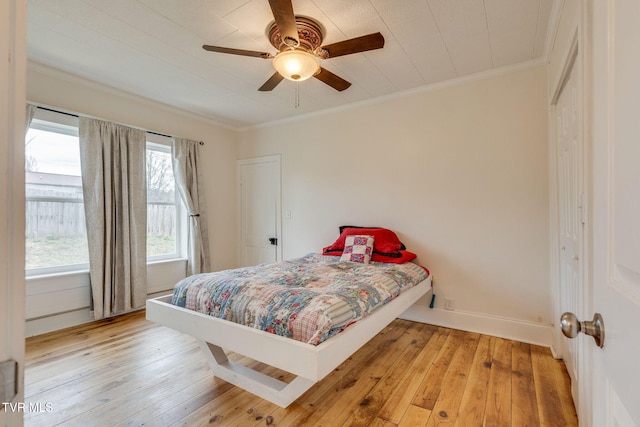 bedroom with a ceiling fan, baseboards, crown molding, and hardwood / wood-style floors