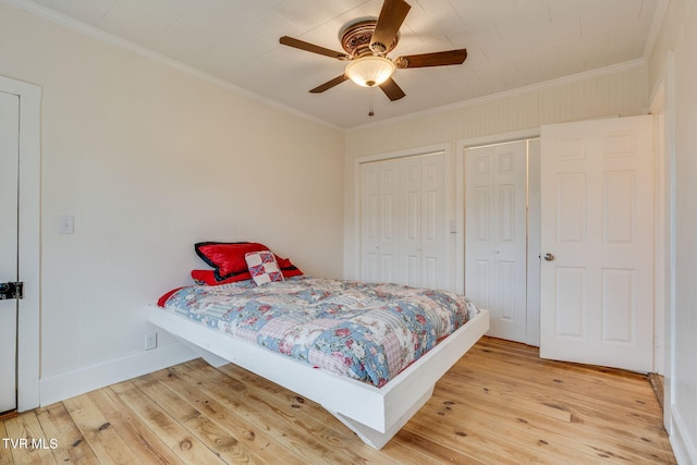 bedroom with light wood-style flooring, ornamental molding, and multiple closets