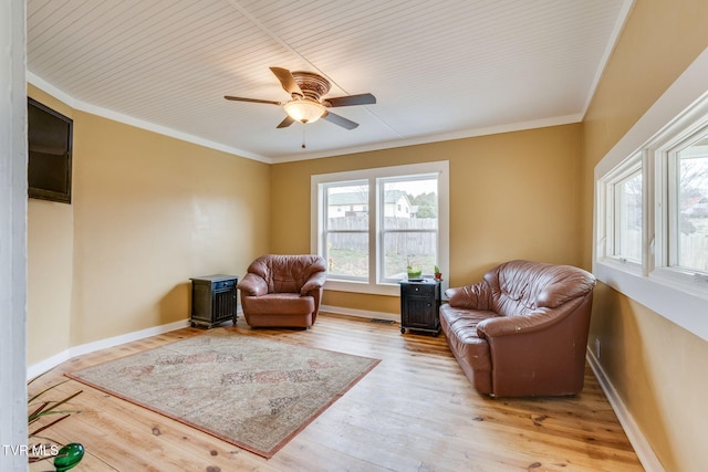 sitting room featuring baseboards, wood finished floors, and crown molding