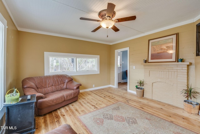 living area with ornamental molding, wood finished floors, a ceiling fan, and baseboards