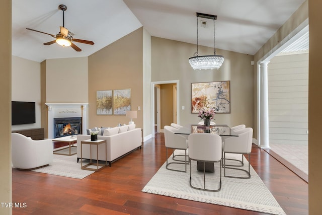 dining area featuring a ceiling fan, a glass covered fireplace, high vaulted ceiling, and wood finished floors