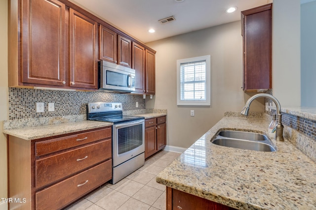 kitchen with light tile patterned floors, stainless steel appliances, a sink, visible vents, and backsplash