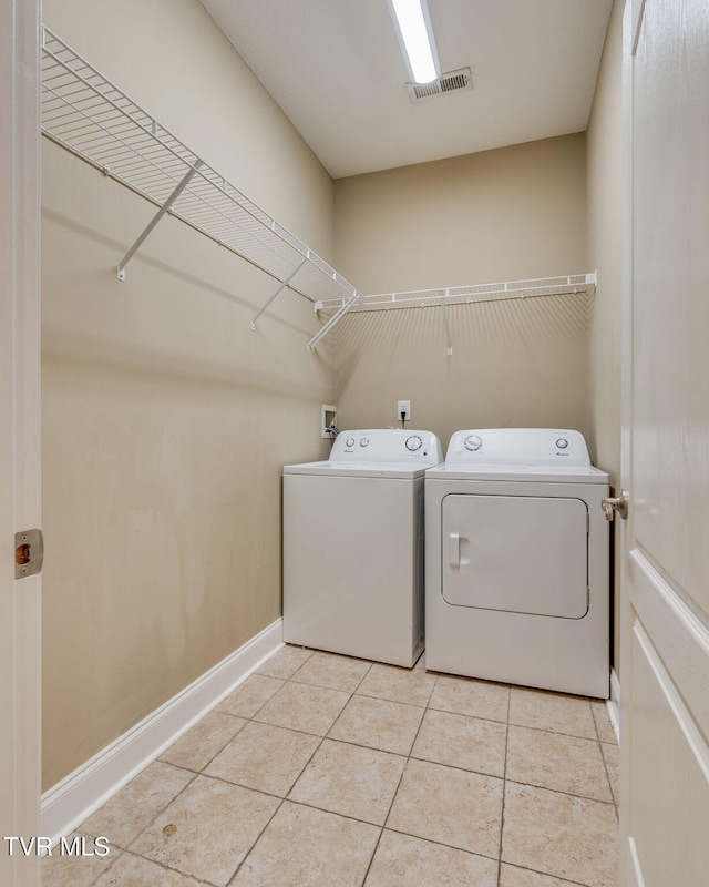 washroom with light tile patterned floors, laundry area, visible vents, baseboards, and washer and dryer