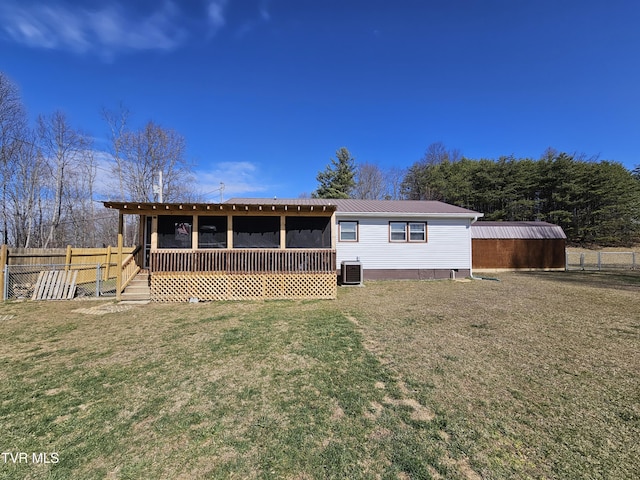 rear view of property with a lawn, metal roof, fence, and central air condition unit