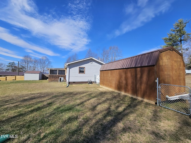 exterior space with an outbuilding, metal roof, fence, a gambrel roof, and a lawn