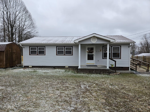 view of front of home with an outbuilding, metal roof, a storage shed, fence, and crawl space