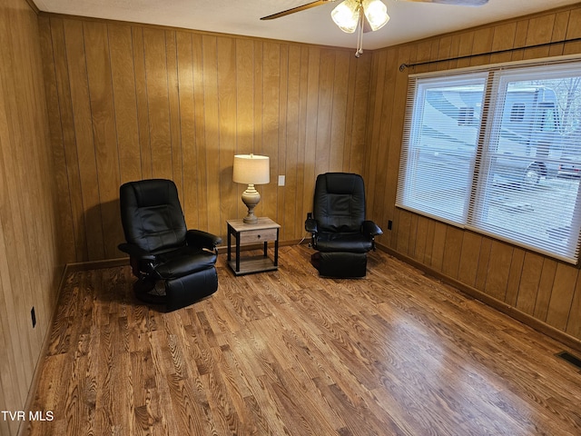 sitting room with wood walls, plenty of natural light, and wood finished floors