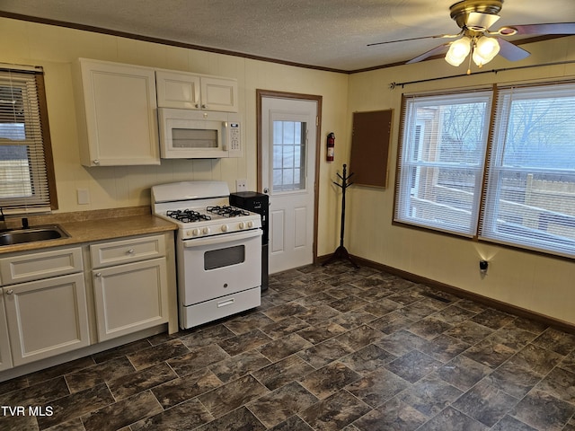 kitchen with white appliances, ornamental molding, white cabinets, and a sink