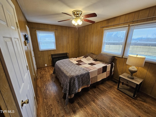 bedroom featuring multiple windows, wood walls, and wood finished floors