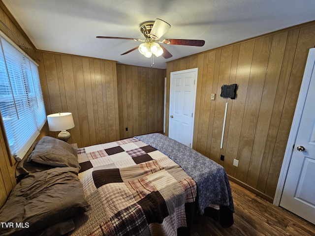 bedroom with wooden walls, dark wood finished floors, and a ceiling fan