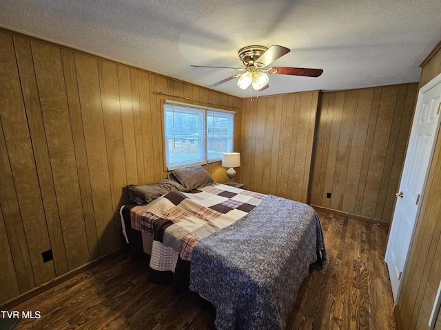 bedroom with wooden walls, ceiling fan, a textured ceiling, and wood finished floors