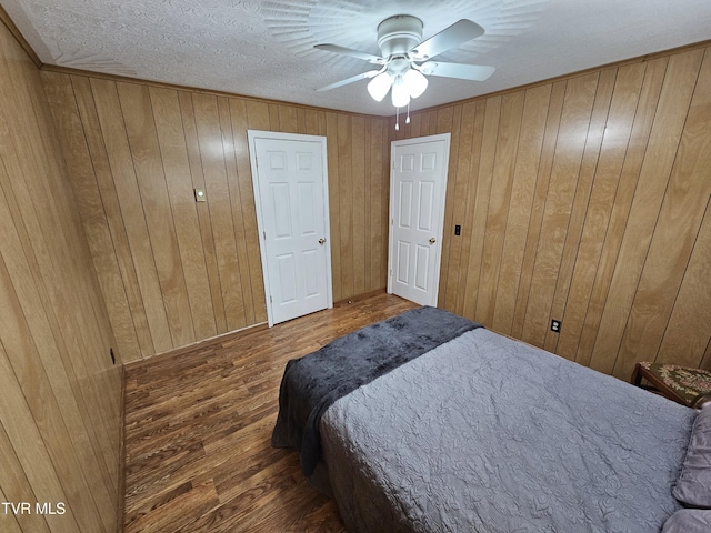 bedroom with wood walls, a ceiling fan, and wood finished floors