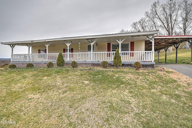 farmhouse-style home featuring aphalt driveway, a porch, an attached carport, and a front yard