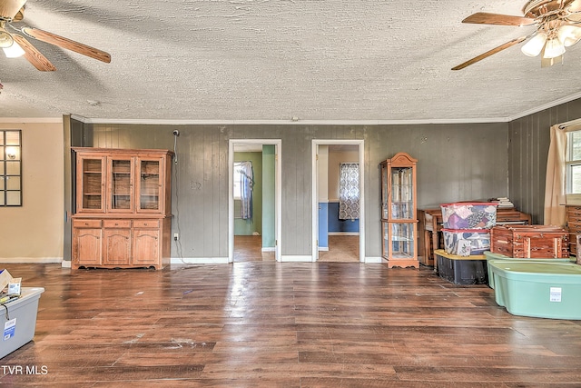 living area with a textured ceiling, a ceiling fan, crown molding, and wood finished floors