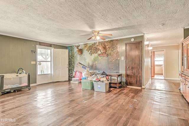 interior space featuring crown molding, hardwood / wood-style floors, a ceiling fan, a textured ceiling, and baseboards