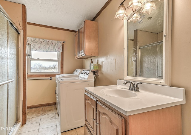 laundry area featuring a textured ceiling, light tile patterned flooring, washing machine and dryer, a sink, and ornamental molding