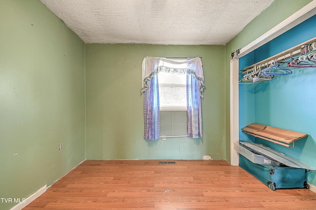 bedroom with a textured ceiling, visible vents, and wood finished floors