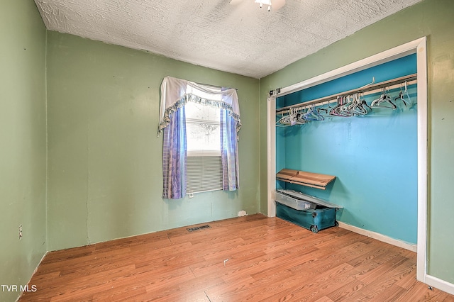 unfurnished bedroom featuring visible vents, a textured ceiling, and wood finished floors