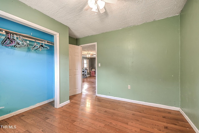 unfurnished bedroom with a textured ceiling, ceiling fan, wood finished floors, and baseboards