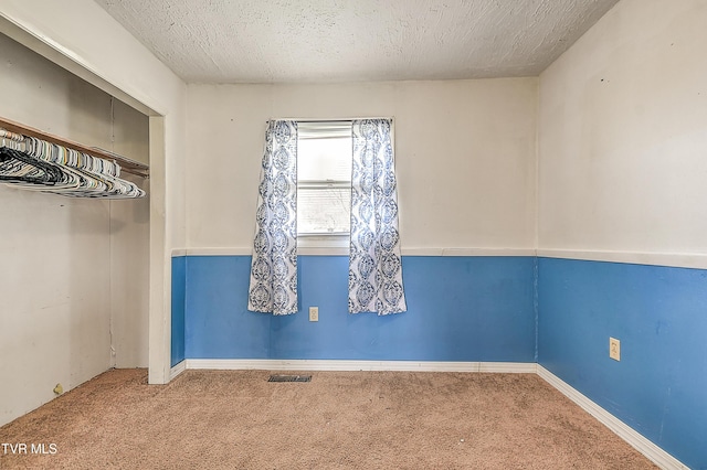 unfurnished room featuring carpet, visible vents, and a textured ceiling