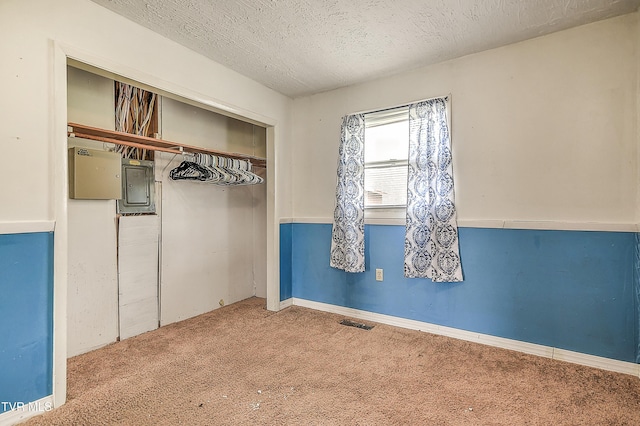 unfurnished bedroom with carpet floors, a closet, visible vents, a textured ceiling, and electric panel