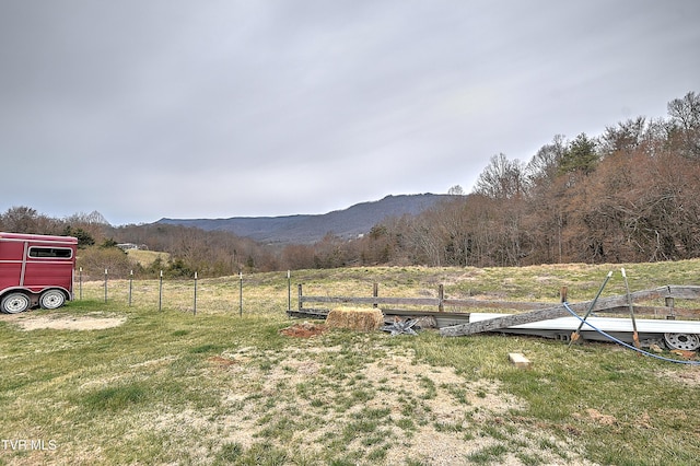 view of yard with a rural view, fence, and a mountain view