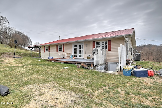 view of front of house with metal roof, a wooden deck, a front lawn, and central air condition unit