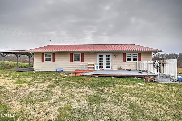 back of house with metal roof, a yard, a wooden deck, and fence