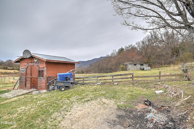 view of yard with an outbuilding, a storage unit, a rural view, and fence