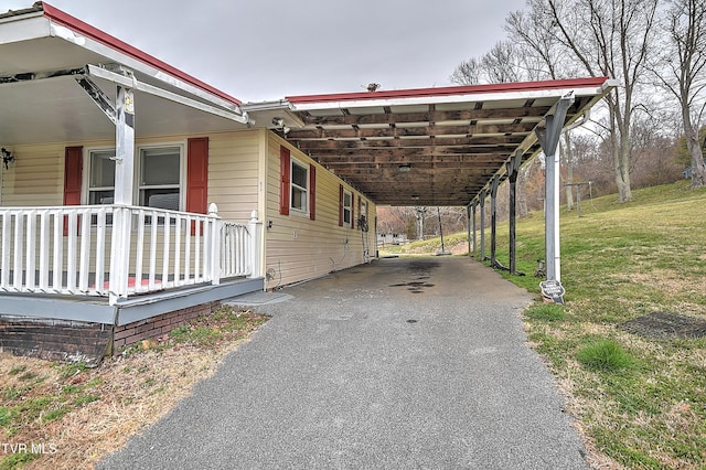 view of property exterior with a porch, a lawn, aphalt driveway, and a carport