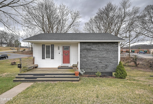 view of front facade featuring a shingled roof and a front yard