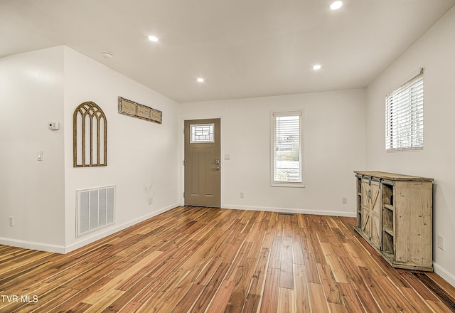 foyer entrance with baseboards, plenty of natural light, visible vents, and light wood-style floors