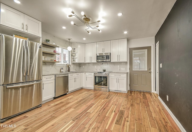 kitchen with stainless steel appliances, white cabinets, a sink, and open shelves