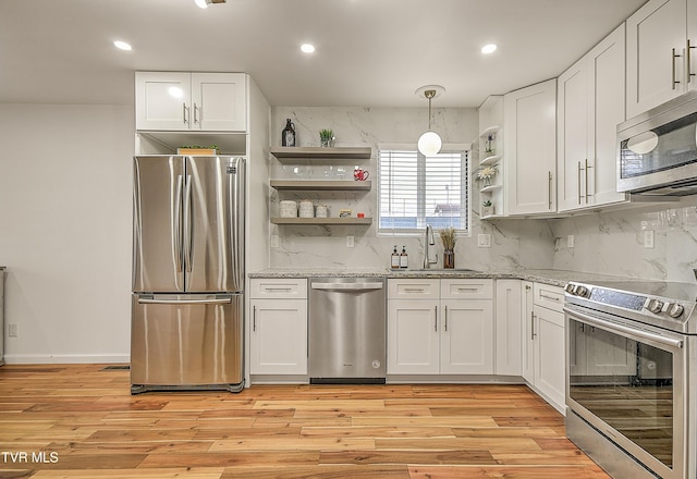 kitchen featuring open shelves, stainless steel appliances, light wood-style flooring, white cabinetry, and a sink