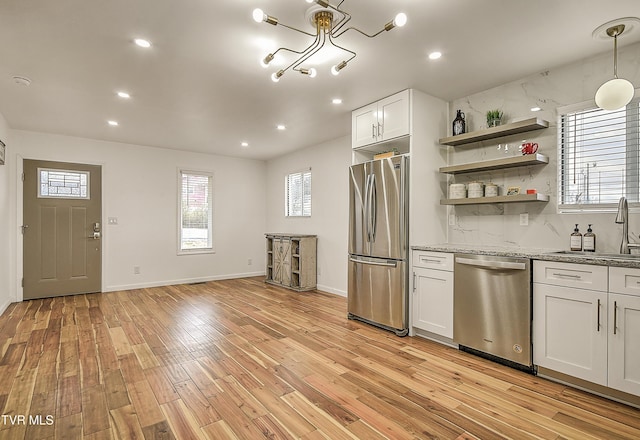 kitchen with open shelves, stainless steel appliances, backsplash, light wood-style flooring, and a sink