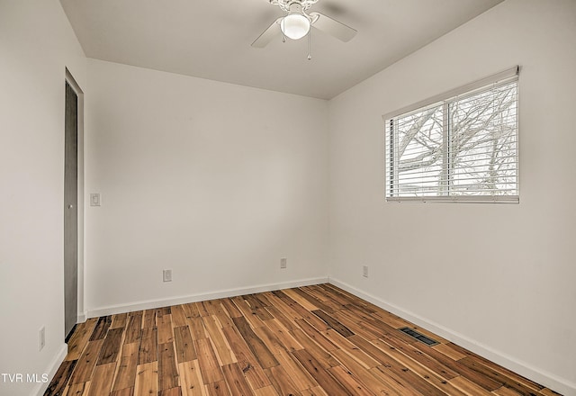 spare room with a ceiling fan, visible vents, baseboards, and wood finished floors