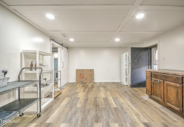 workout room with a wealth of natural light, recessed lighting, light wood-style flooring, a barn door, and baseboards