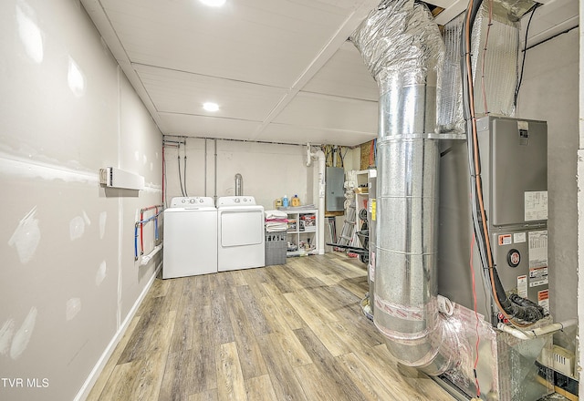 finished below grade area featuring electric panel, baseboards, washer and clothes dryer, and wood finished floors