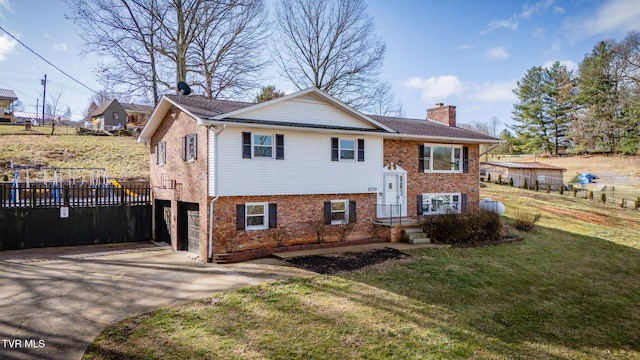 bi-level home with brick siding, fence, concrete driveway, a chimney, and a front yard