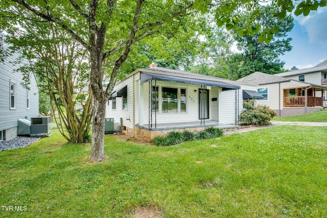 view of front of home with central air condition unit, covered porch, and a front yard