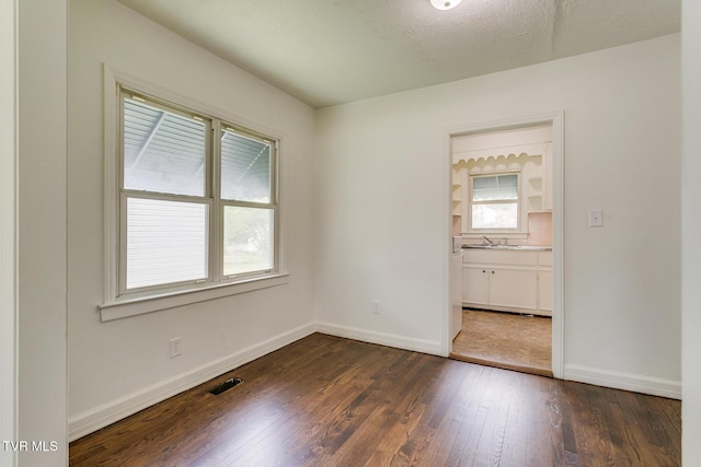 unfurnished room with visible vents, dark wood-style flooring, and baseboards