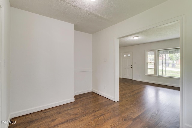 spare room with baseboards, dark wood-type flooring, and a textured ceiling