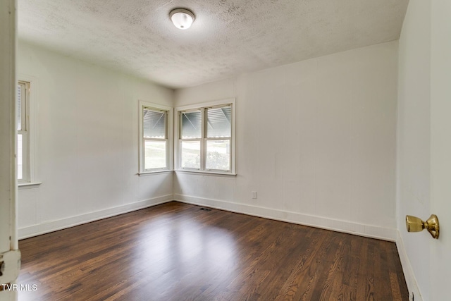 empty room with baseboards, dark wood-type flooring, and a textured ceiling