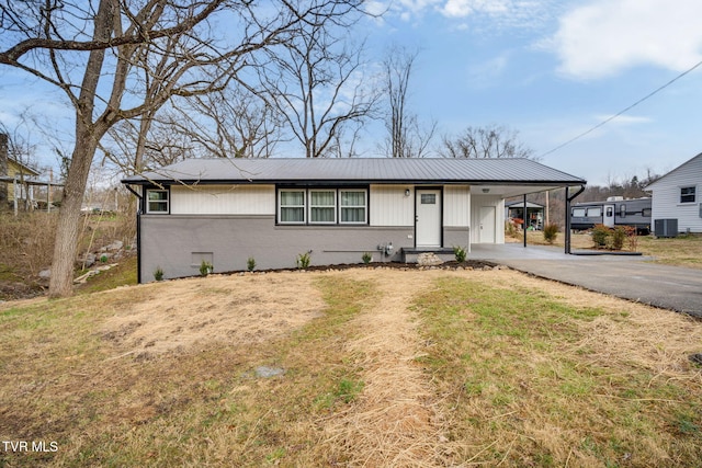 view of front of property featuring central air condition unit, driveway, a carport, a front yard, and brick siding