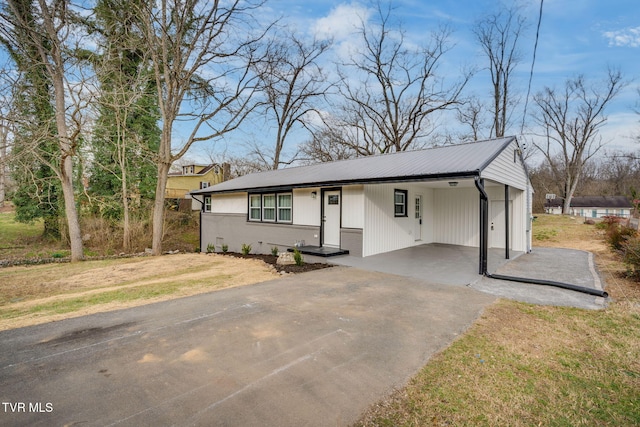 view of front of house with an attached carport, driveway, metal roof, and a front yard