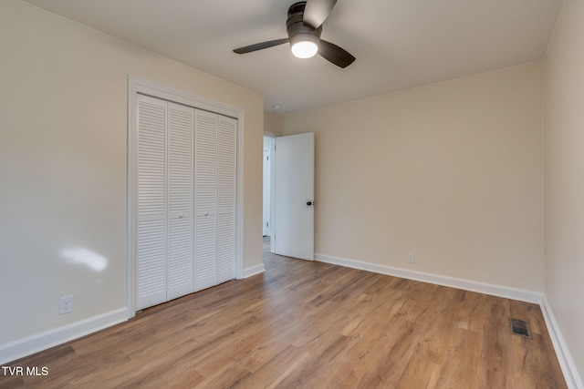 unfurnished bedroom featuring visible vents, ceiling fan, baseboards, wood finished floors, and a closet