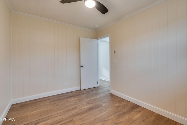 spare room featuring light wood-style flooring, ornamental molding, baseboards, and ceiling fan